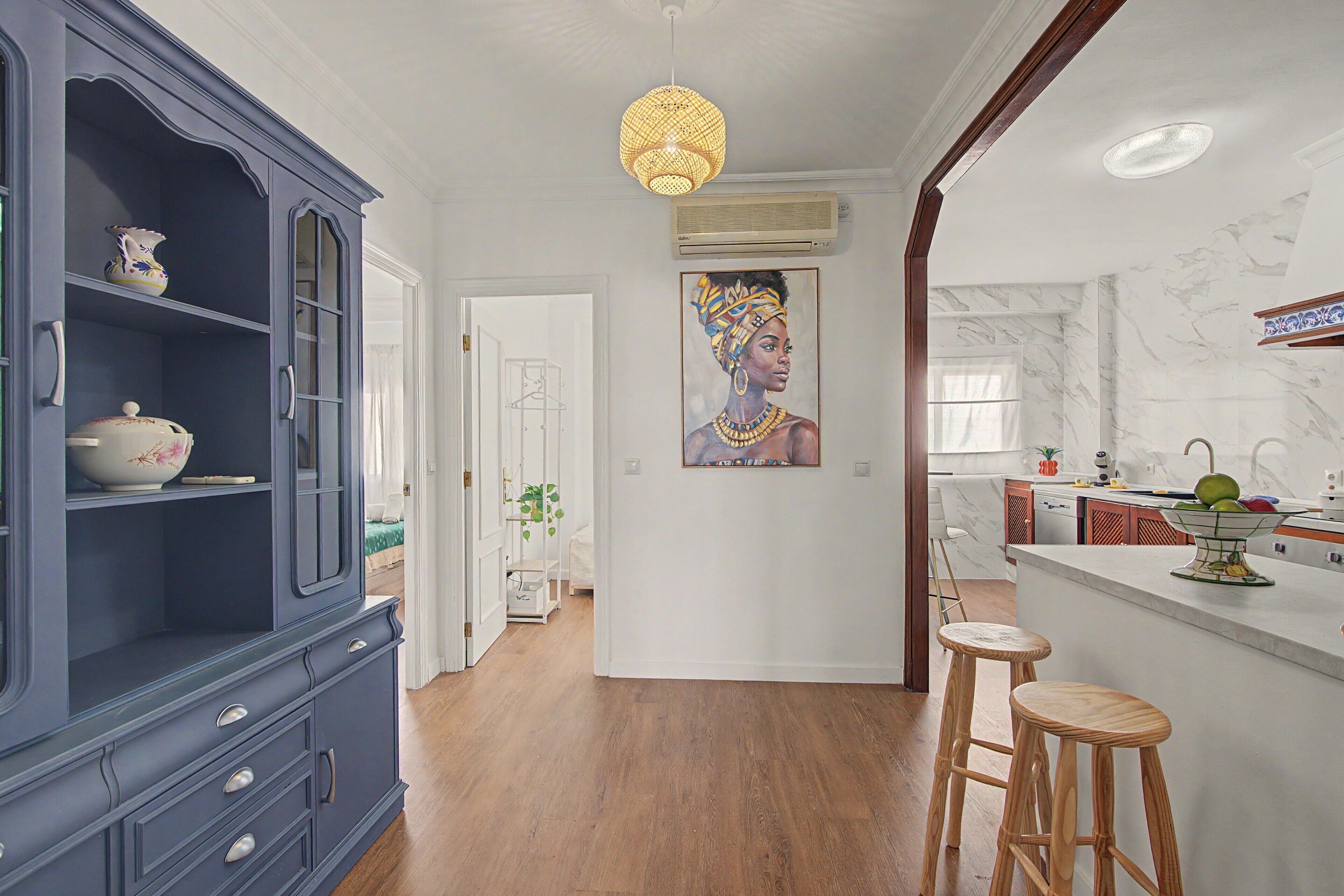 A modern kitchen with a marble backsplash, wooden stools, and a painting on the wall.