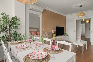 A modern living room with a dining area, a flat-screen TV, and a large plant. - Apartment 'Brisa del Sur' (Isla Canela) for 6 guests, Huelva & Portugal, Wi-Fi, A/C and bright (Ayamonte)