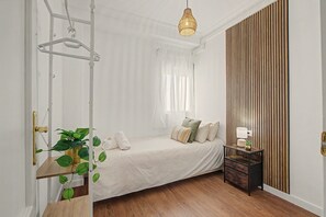 Ein Schlafzimmer mit einem Bett, einem Nachttisch, einer Lampe und einer Pflanze.
