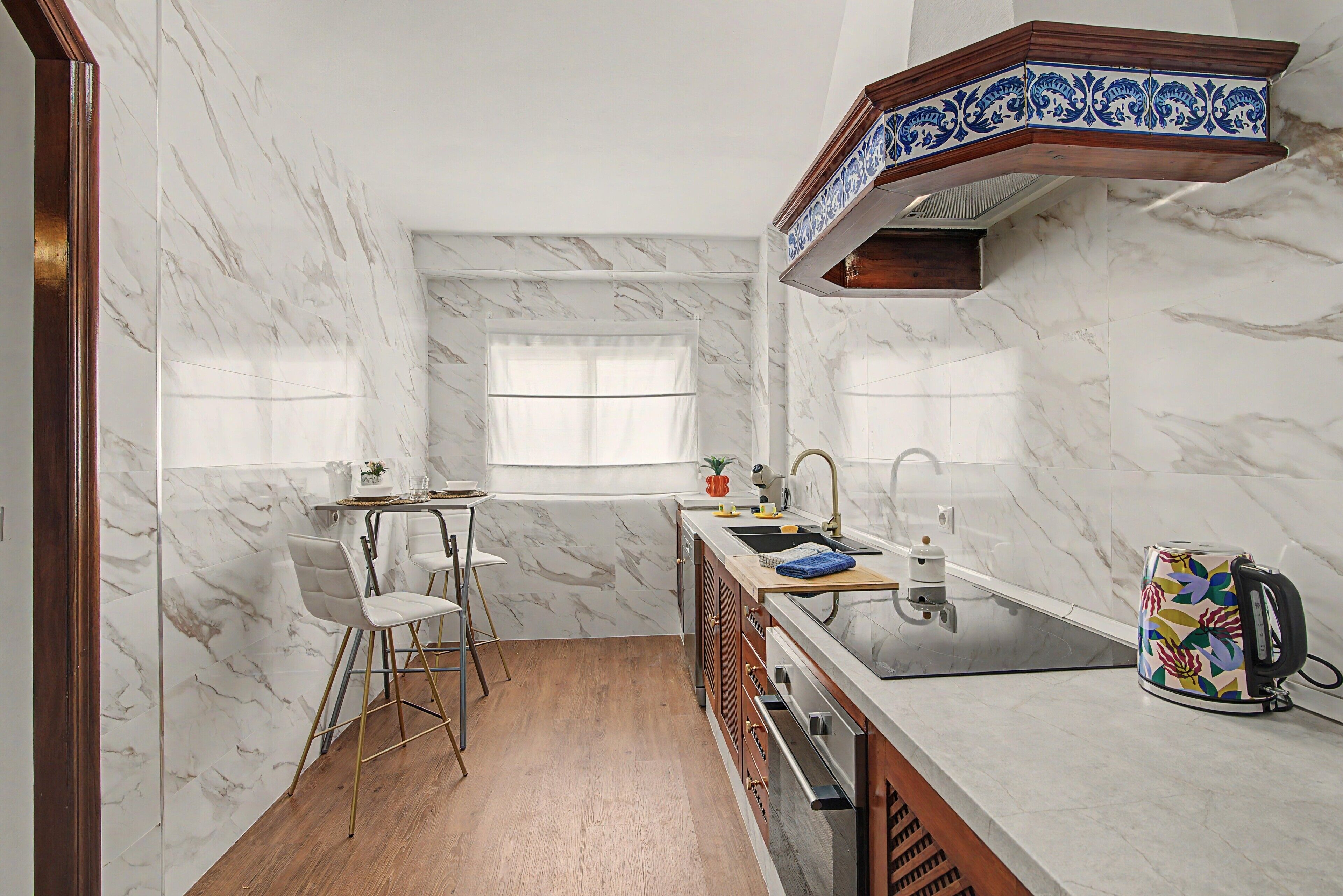 A compact kitchen with a marble backsplash, a window, a sink, and a toaster.
