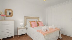 Un dormitorio con cama, mesita de noche, cómoda y armario.