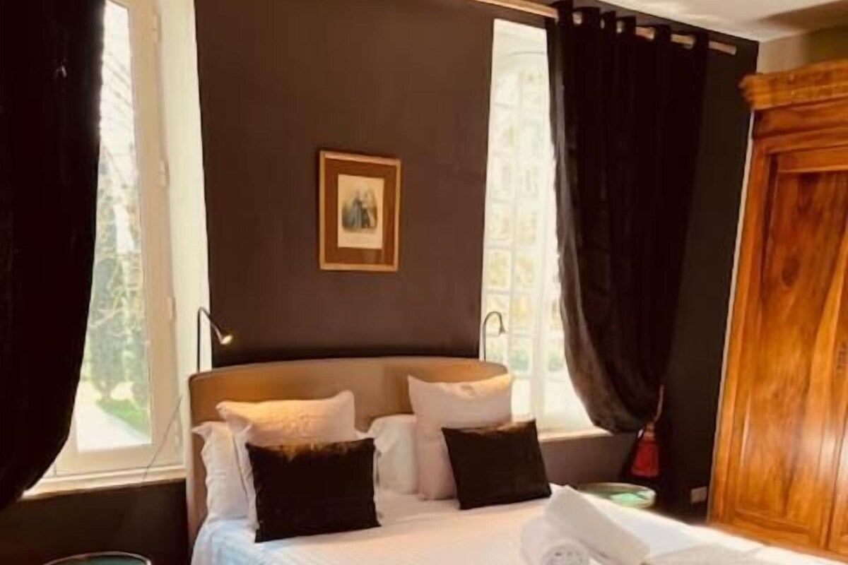 A bedroom with a bed, a bedside table, a window, and a door.