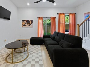 A living room with a sofa, ottoman, and a small table with a checkered rug. - Oma Cozy Homes - Modern New-Construction Retreat in Houston (Houston)