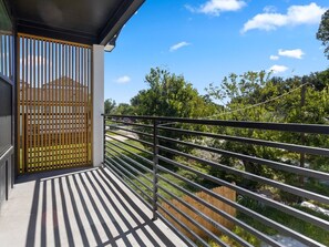 Un balcón con vistas a una zona residencial, un portón de madera y una barandilla de metal.