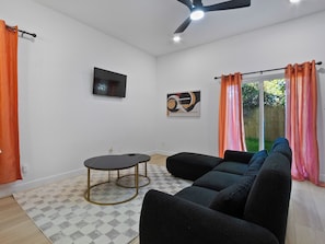 A living room with a black sofa set, a small round table, and a ceiling fan. - Oma Cozy Homes (Houston)