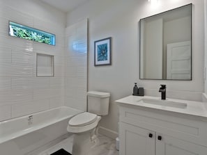A modern bathroom with a bathtub, toilet, and vanity. - Oma Cozy Homes (Houston)