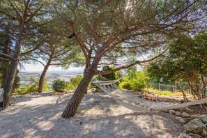 A hammock tied between trees in a natural setting with a view of the landscape.
