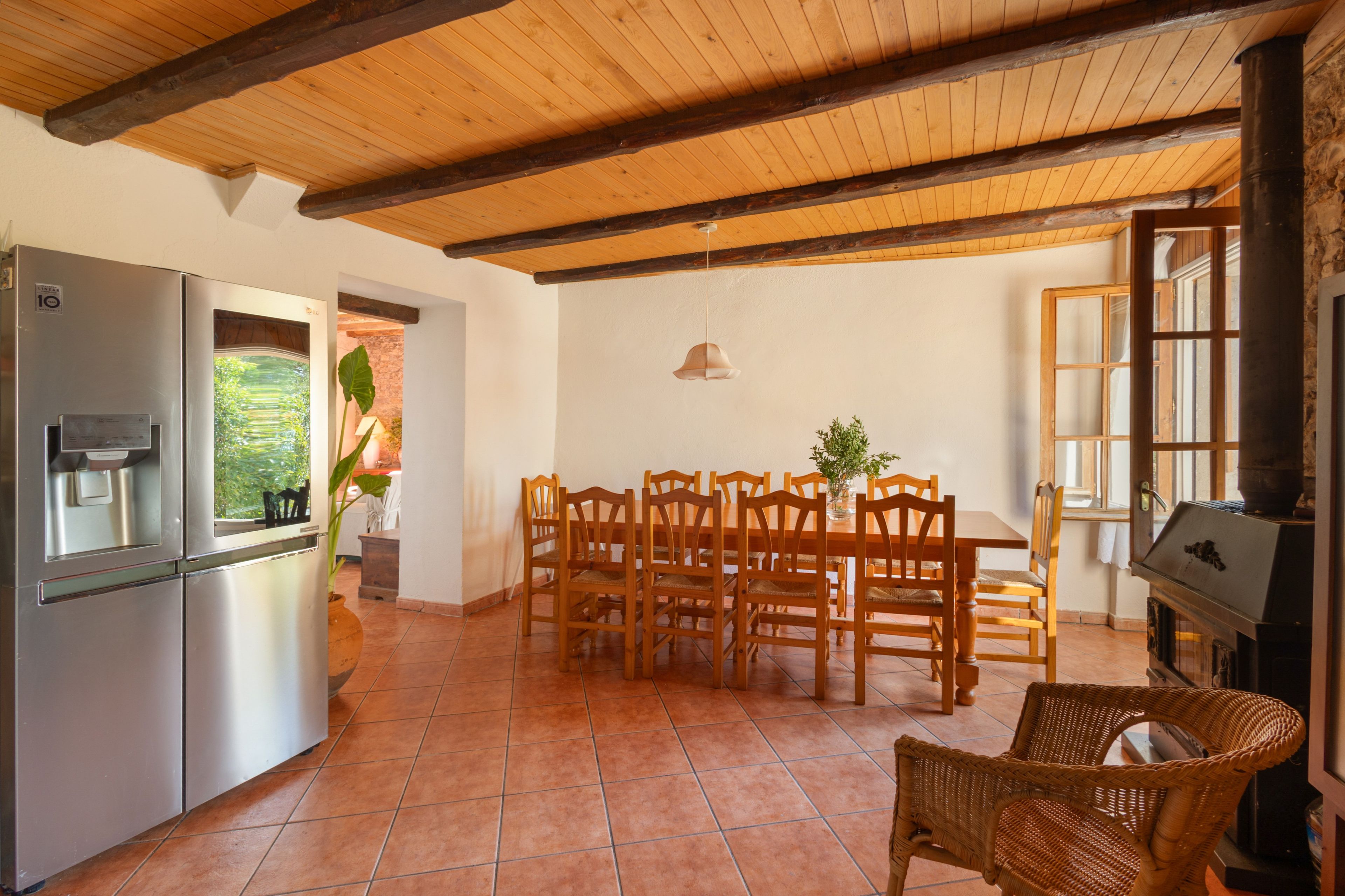 Una cocina con refrigerador, mesa de comedor con sillas y una parrilla.