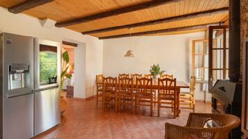 Una cocina con refrigerador, mesa de comedor con sillas y una parrilla.
