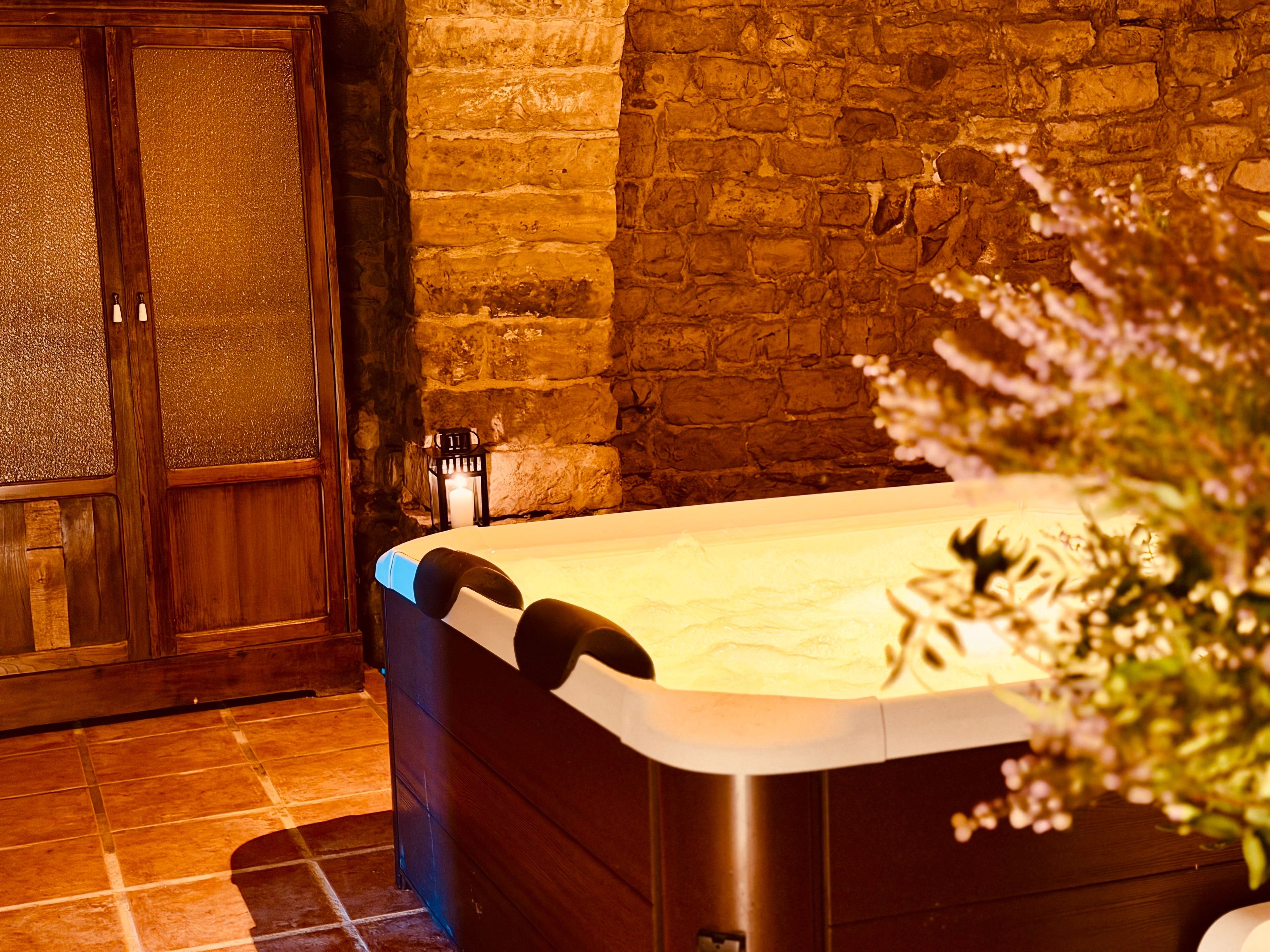 A spa room with a stone wall, a wooden cabinet, and a hot tub.
