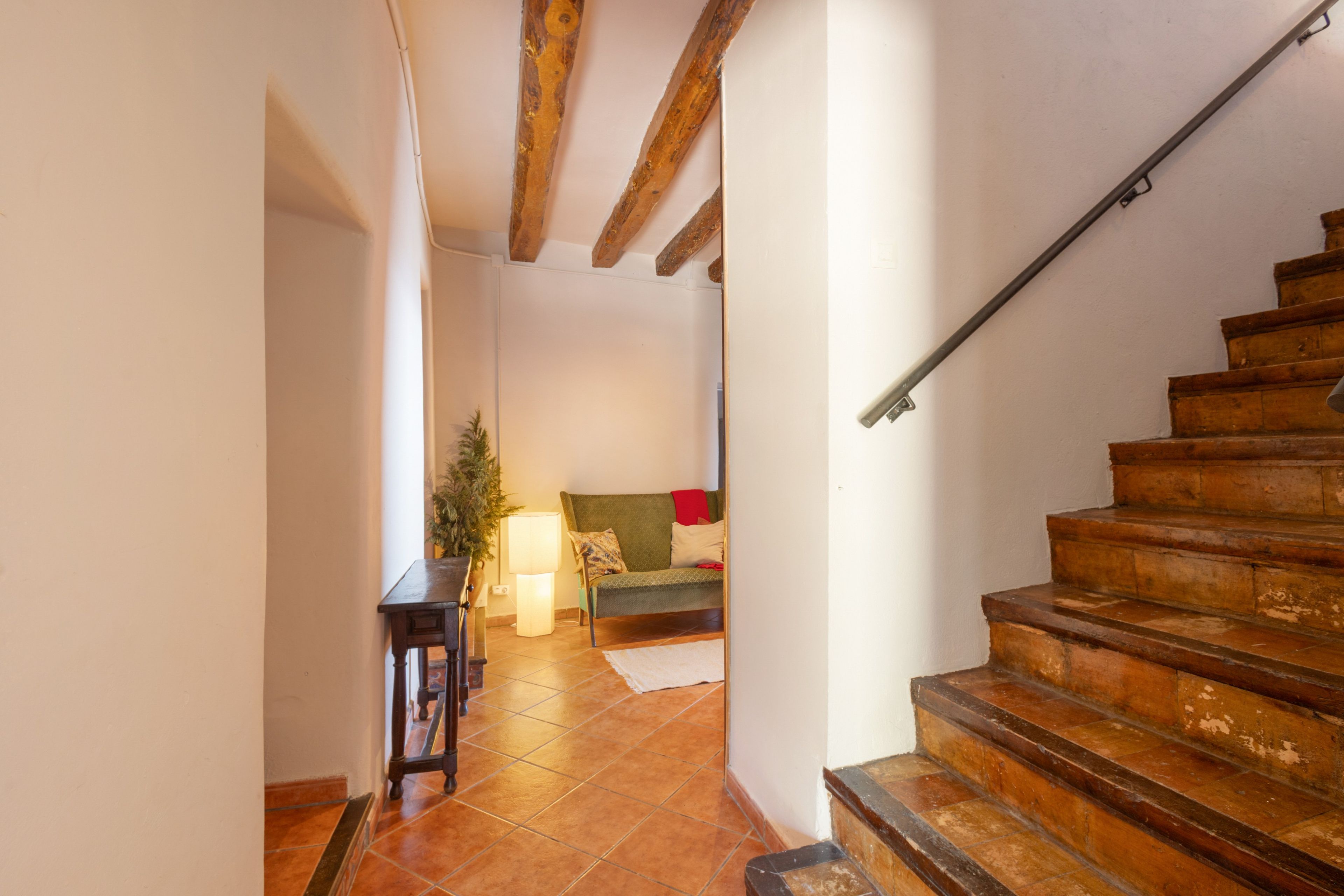 Un escalier menant à un espace de vie comprenant un canapé et une lampe.