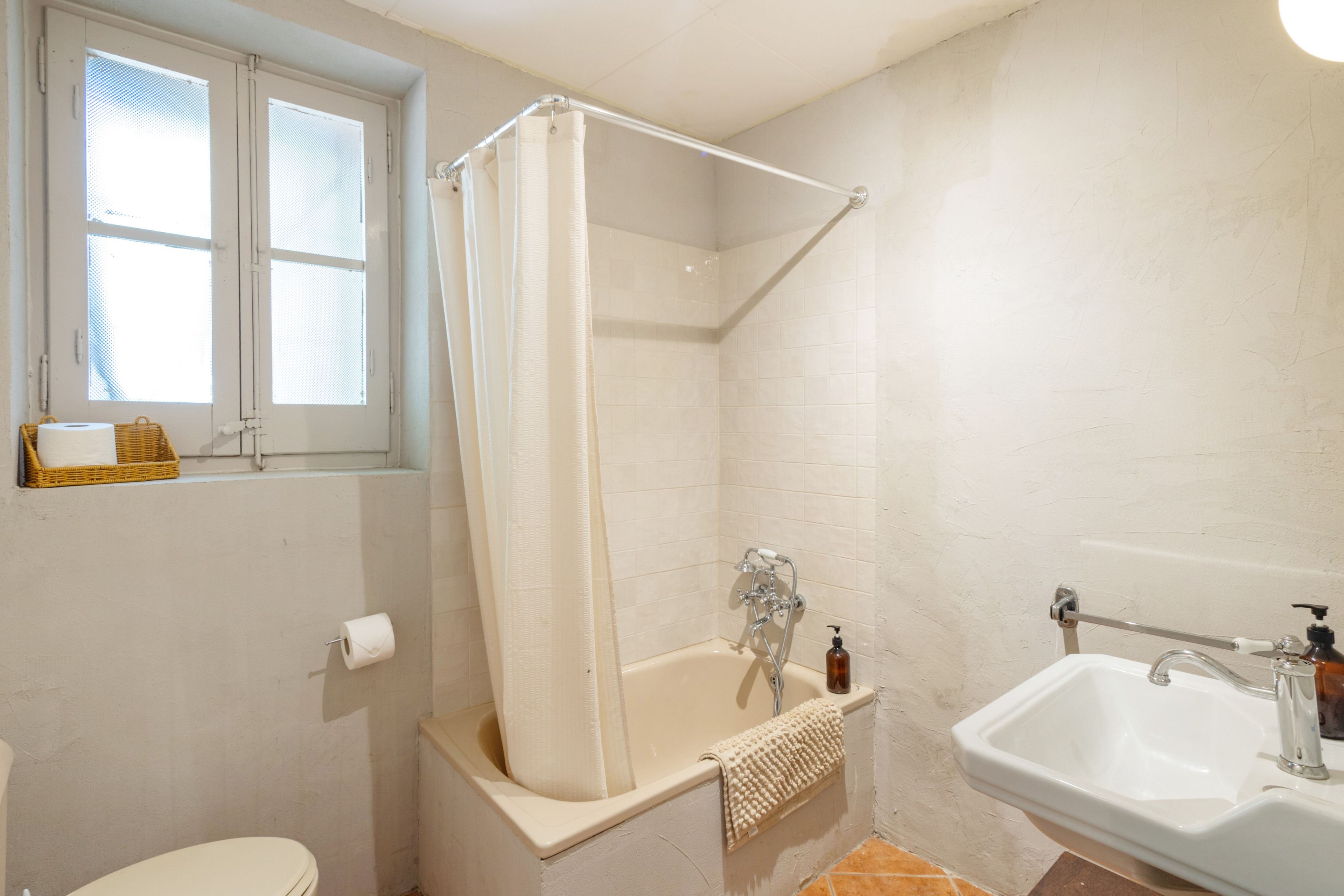 Un baño con bañera, cortina de ducha, inodoro y lavamanos.