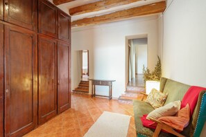 Amplia sala de estar con un armario de madera, un sofá con cojines, una mesita y una escalera que conduce a otra habitación.