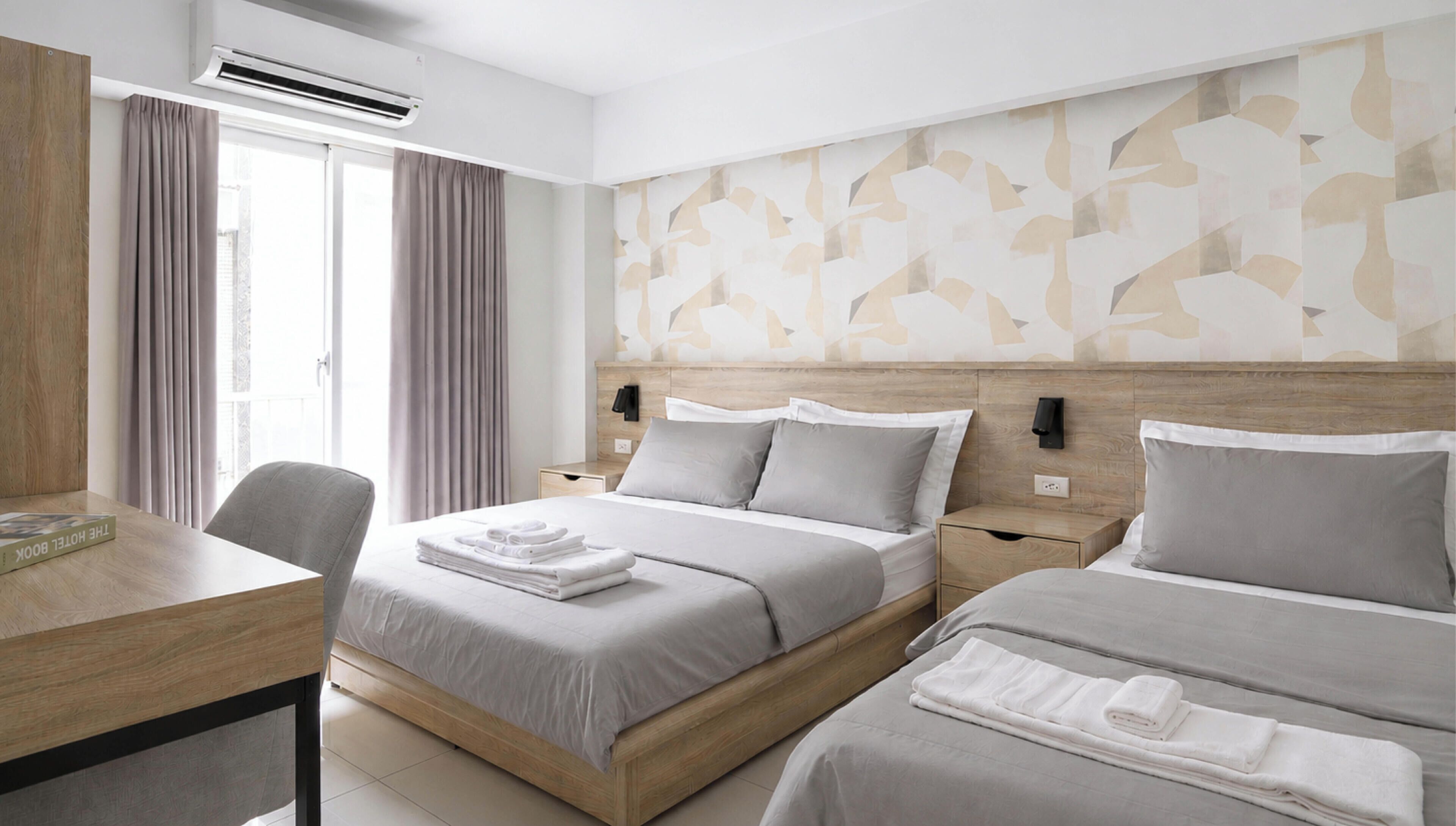 A hotel room with a bed, a desk, and a chair.