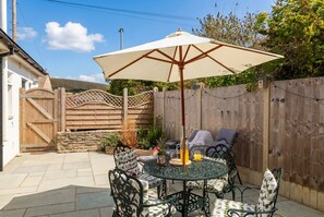 A patio with a round table, chairs, and a large umbrella. - Dog Friendly Dorset Escape for 2 (Swanage)