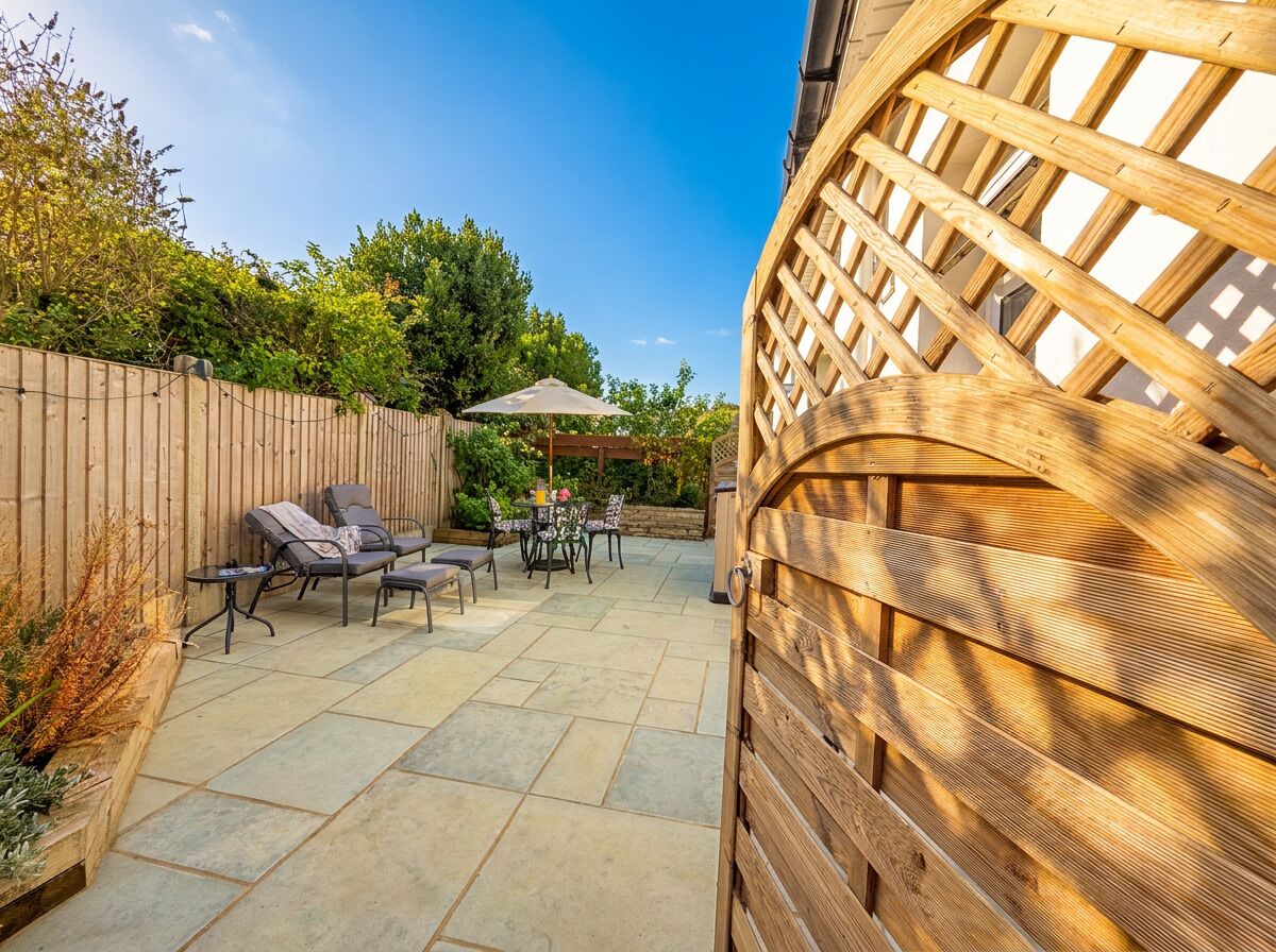 An outdoor patio with a wooden fence, a pergola, and outdoor furniture.