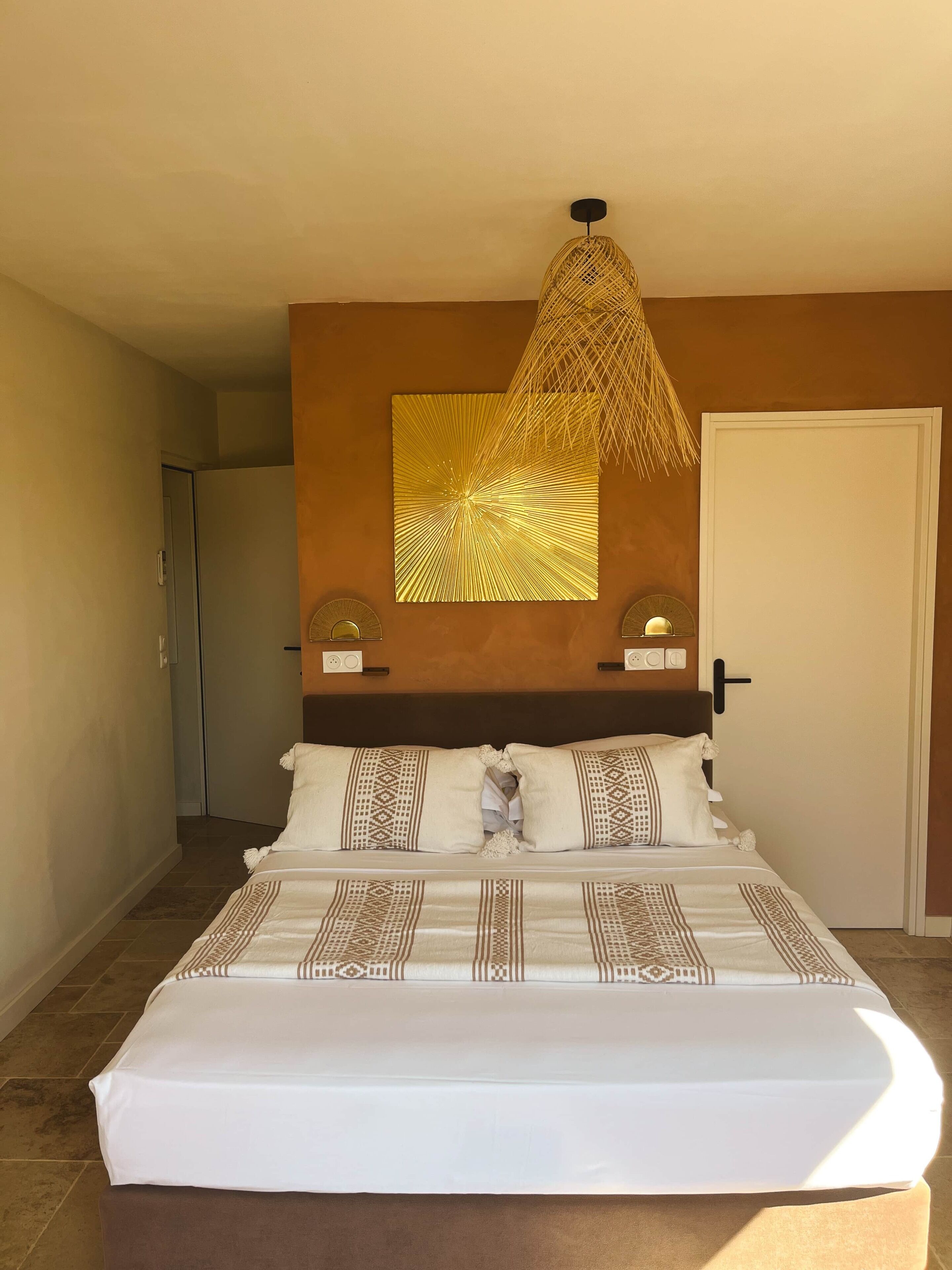 A bedroom with a bed, a wall-mounted light fixture, and a door.