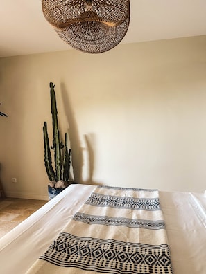 Ett rum med en säng, en hängande lampa och en kaktus.