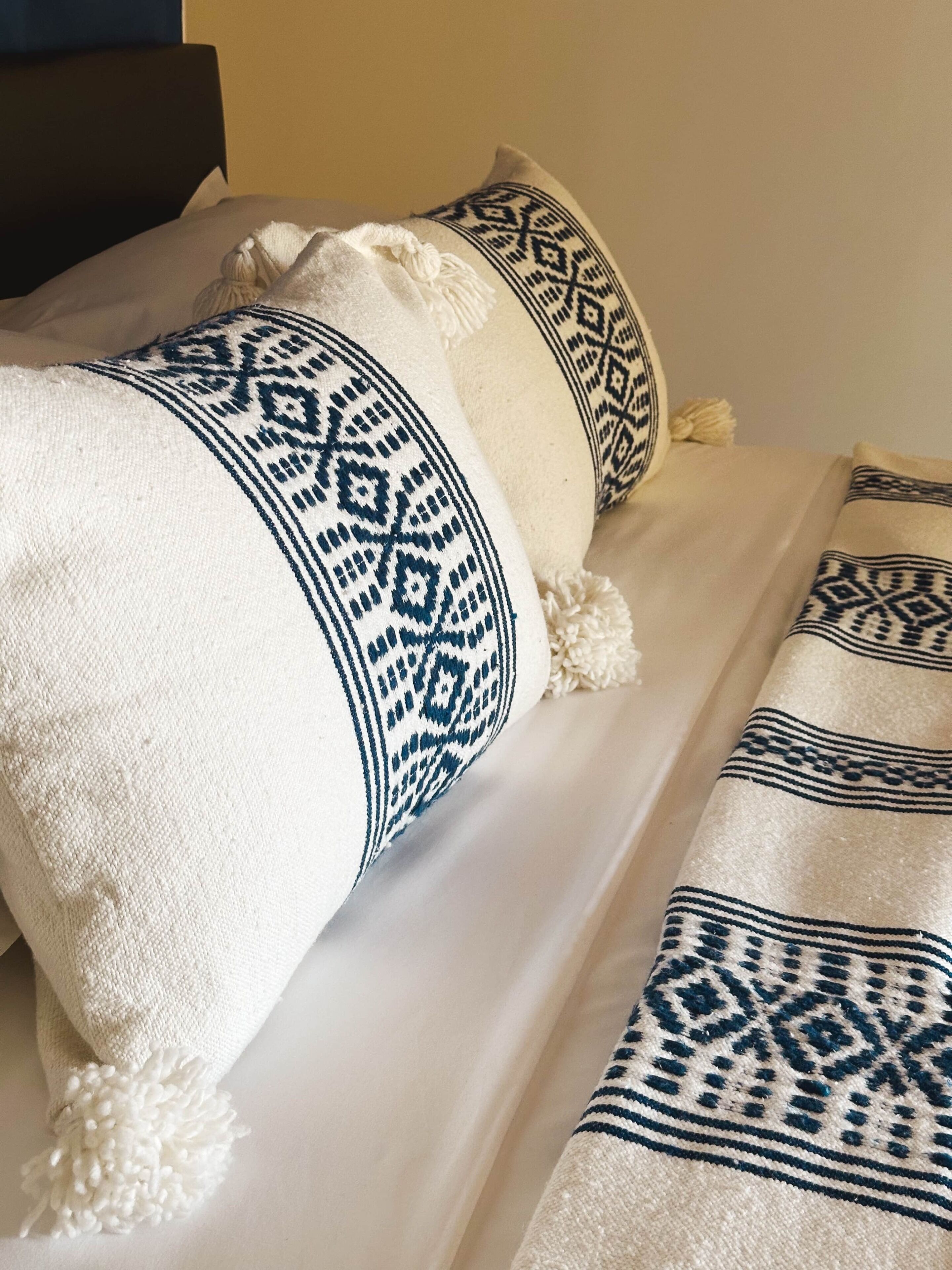 A bed with white bedding and pillows featuring blue geometric patterns.