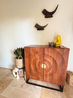 Ett träskåp med en cirkelformad design, en väggmonterad skulptur och en krukväxt.