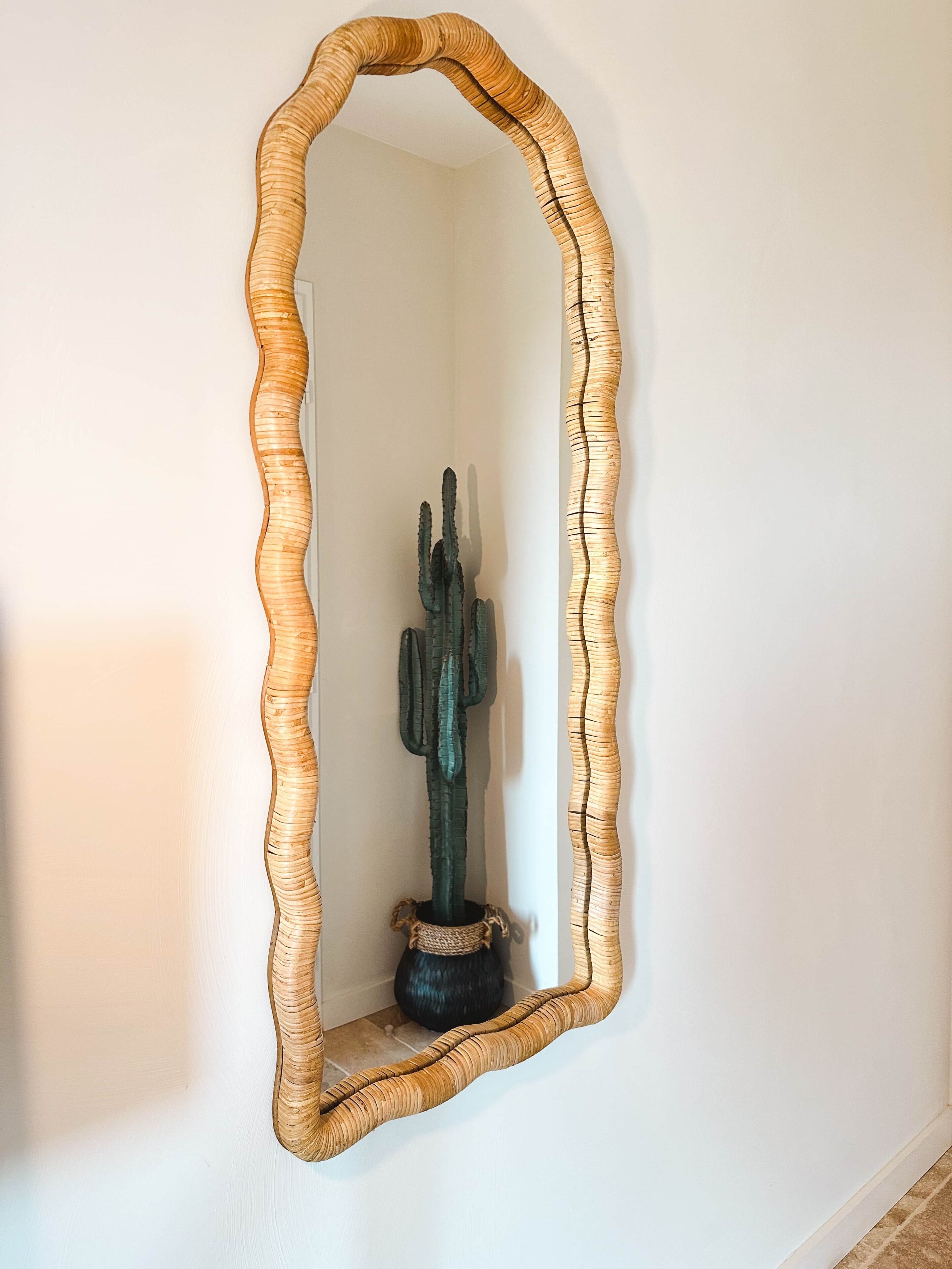 A mirror with a wavy frame on a wall.