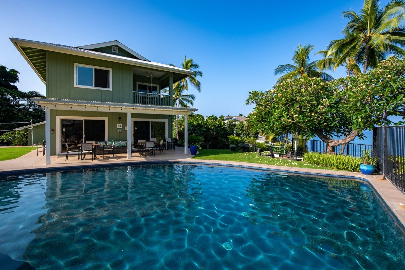A two-story house with a pool, outdoor furniture, and a covered patio.