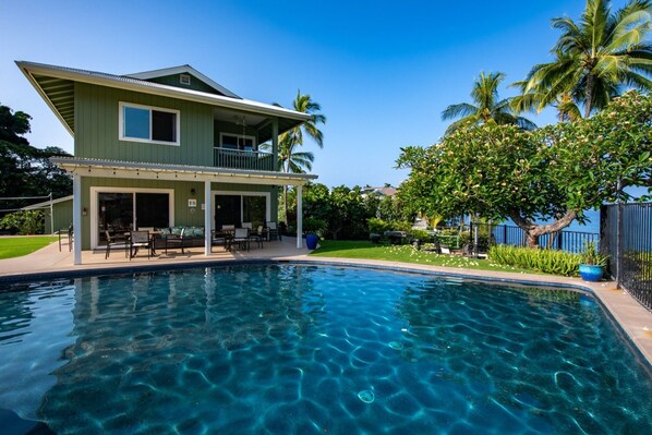 A two-story house with a pool, outdoor furniture, and a covered patio.