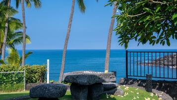 A stone bench, a metal fence, and a clear view of the ocean.