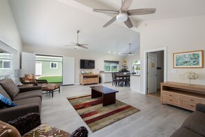 Ein geräumiges Wohnzimmer mit Deckenventilator, Essbereich und Küche.