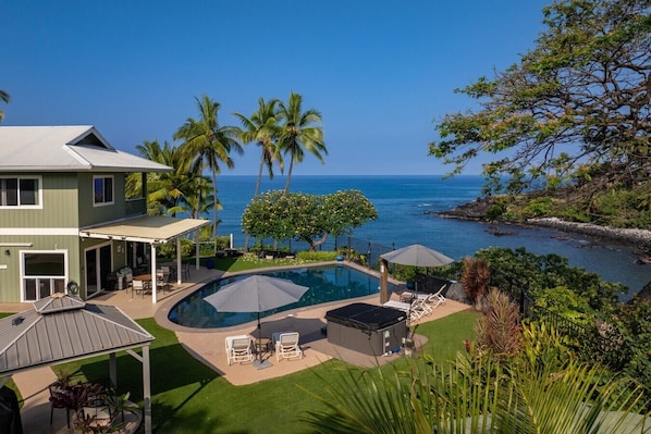Ein Wohnhaus mit Swimmingpool, Sitzgelegenheiten im Freien und Blick auf den Ozean.