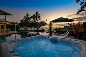 Ein Whirlpool mit Meerblick bei Sonnenuntergang, eine überdachte Terrasse und ein Pool.