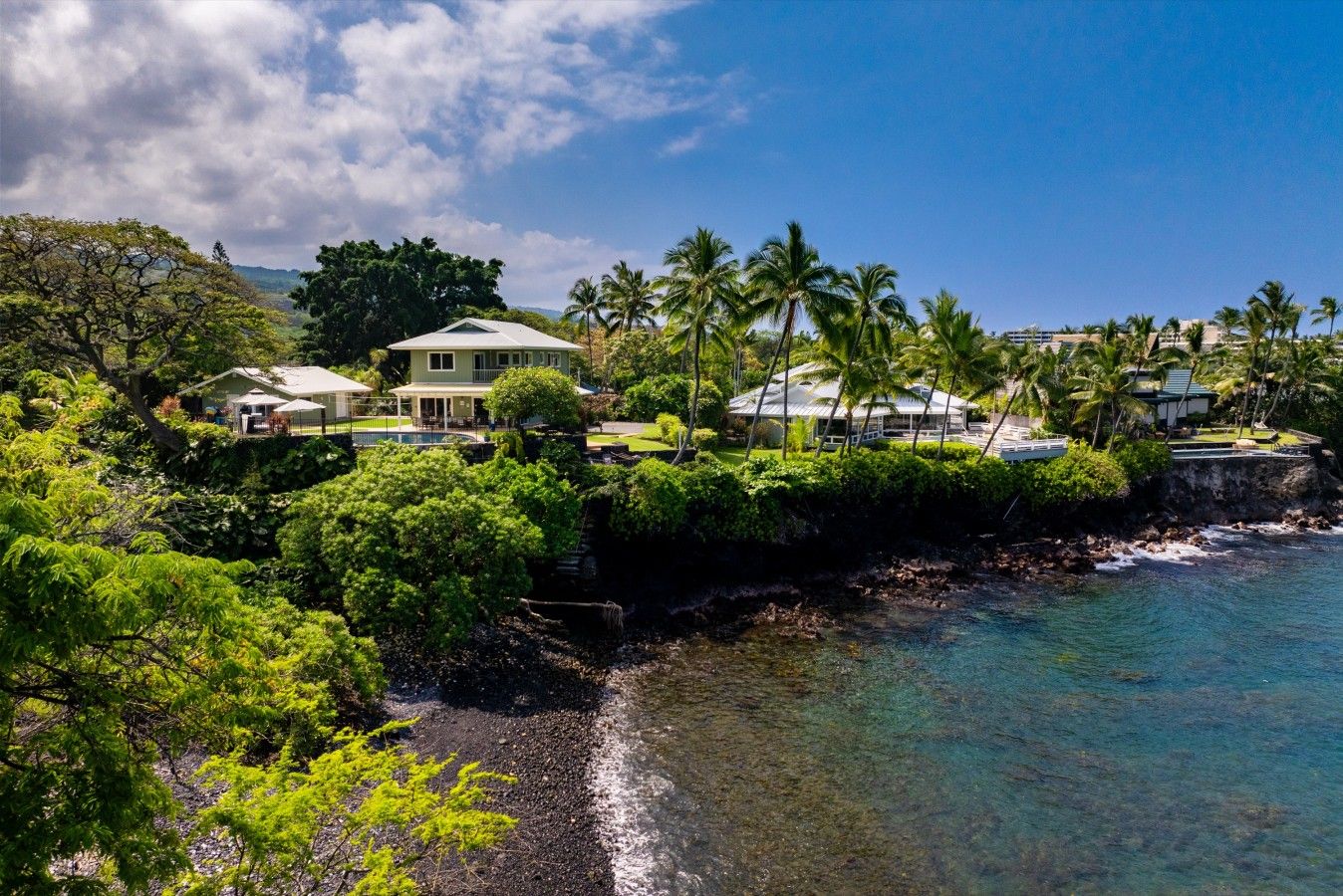 A coastal property with multiple houses, a rocky shoreline, and lush greenery.