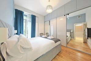 A modern bedroom with a large bed, a bedside table, a chair, a mirror, and a wardrobe. - Spacious & stylish 2 bedroom apartment in Kentish Town (London)