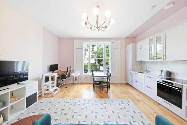 A modern apartment with a dining area, kitchen, and a large window. - Spacious & stylish 2 bedroom apartment in Kentish Town (London)