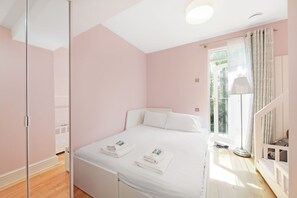 Een slaapkamer met een bed, nachtkastje, lamp en raam met gordijnen.