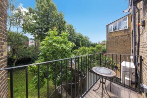 A balcony with a metal railing, a round table, and a potted plant. - Spacious & stylish 2 bedroom apartment in Kentish Town (London)