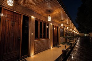 A building with a wooden exterior, multiple doors, and a series of hanging lights. - The Gautam Resort (Varanasi)