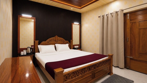Una habitación de hotel con una cama de madera, una mesita de noche, un espejo, un armario y una cortina.