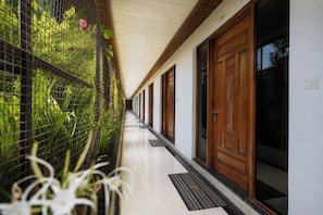 A corridor with a metal fence on one side, wooden doors, and a tiled floor. - The Gautam Resort (Varanasi)
