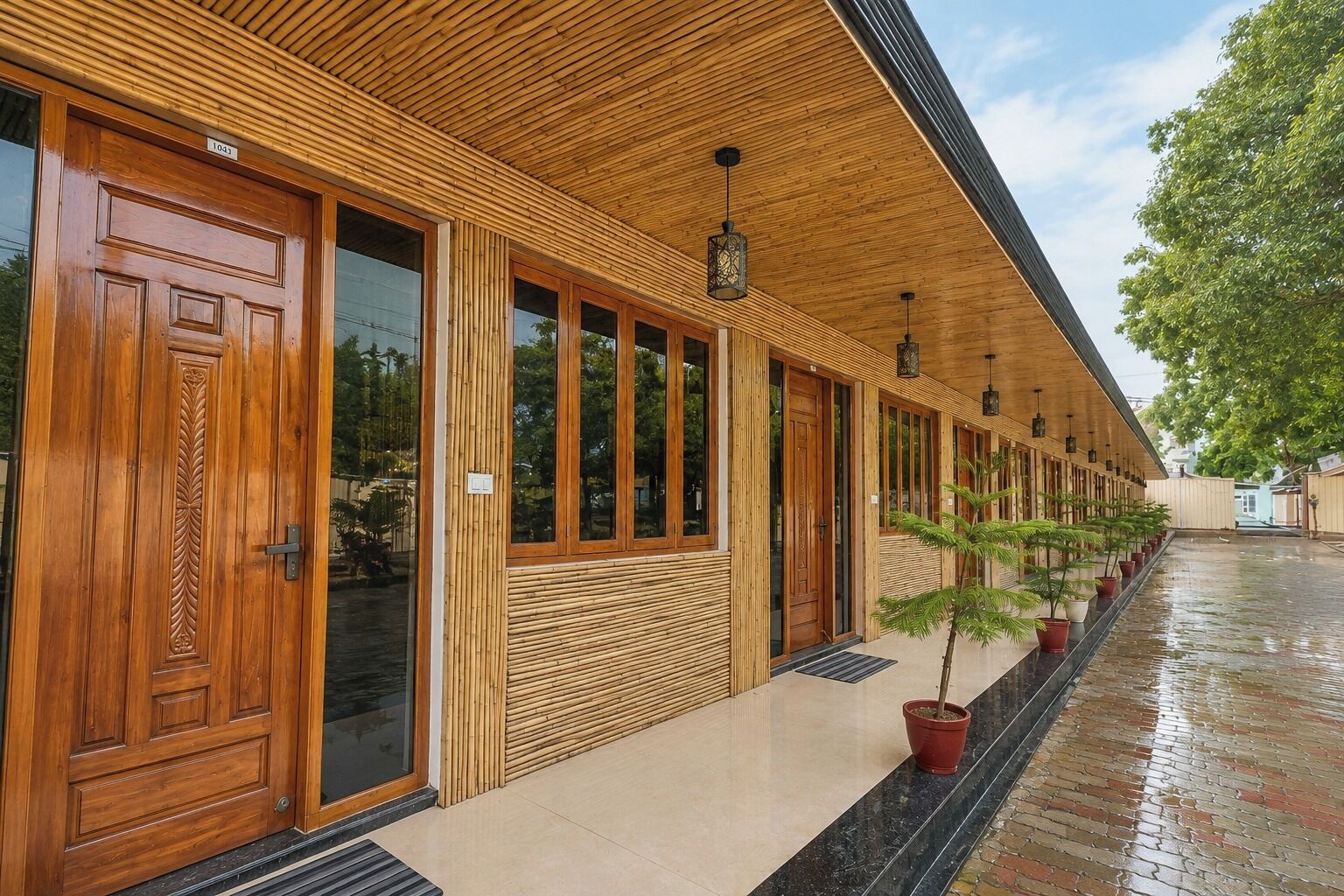A building with a covered walkway, wooden doors, and potted plants.