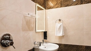 A modern bathroom with a marble vanity, a sink, a mirror, and a towel rack. - The Gautam Resort (Varanasi)
