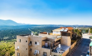 Un edificio de varios pisos con fachada de ladrillo, varios balcones e paneles solares.