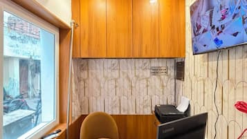 Un mostrador de recepción con una computadora, una silla y una ventana.