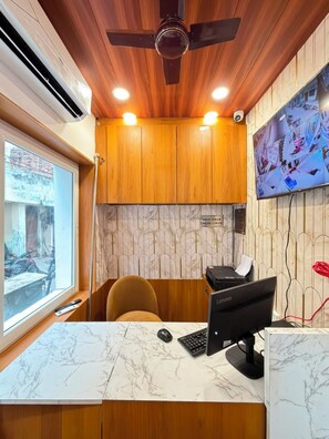 Un mostrador de recepción con una computadora, una silla y una ventana.