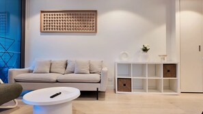 A modern living room with a white sofa, a coffee table, and a white console table with decorative items. - The Glasshouse in the Sky | City View Escape (Brisbane City)
