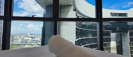 Una cama con vista a un edificio moderno de arquitectura curva y cielo despejado.