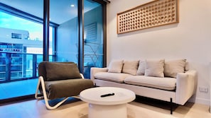 A modern living room with a sofa, a chair, and a coffee table. - The Glasshouse in the Sky | City View Escape (Brisbane City)