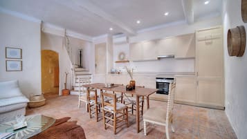 A modern kitchen with white cabinets, a dining table with chairs, and a staircase leading to an upper level.