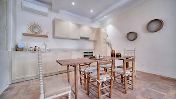 A kitchen with a dining table and chairs, a built-in oven, and a hanging light fixture.