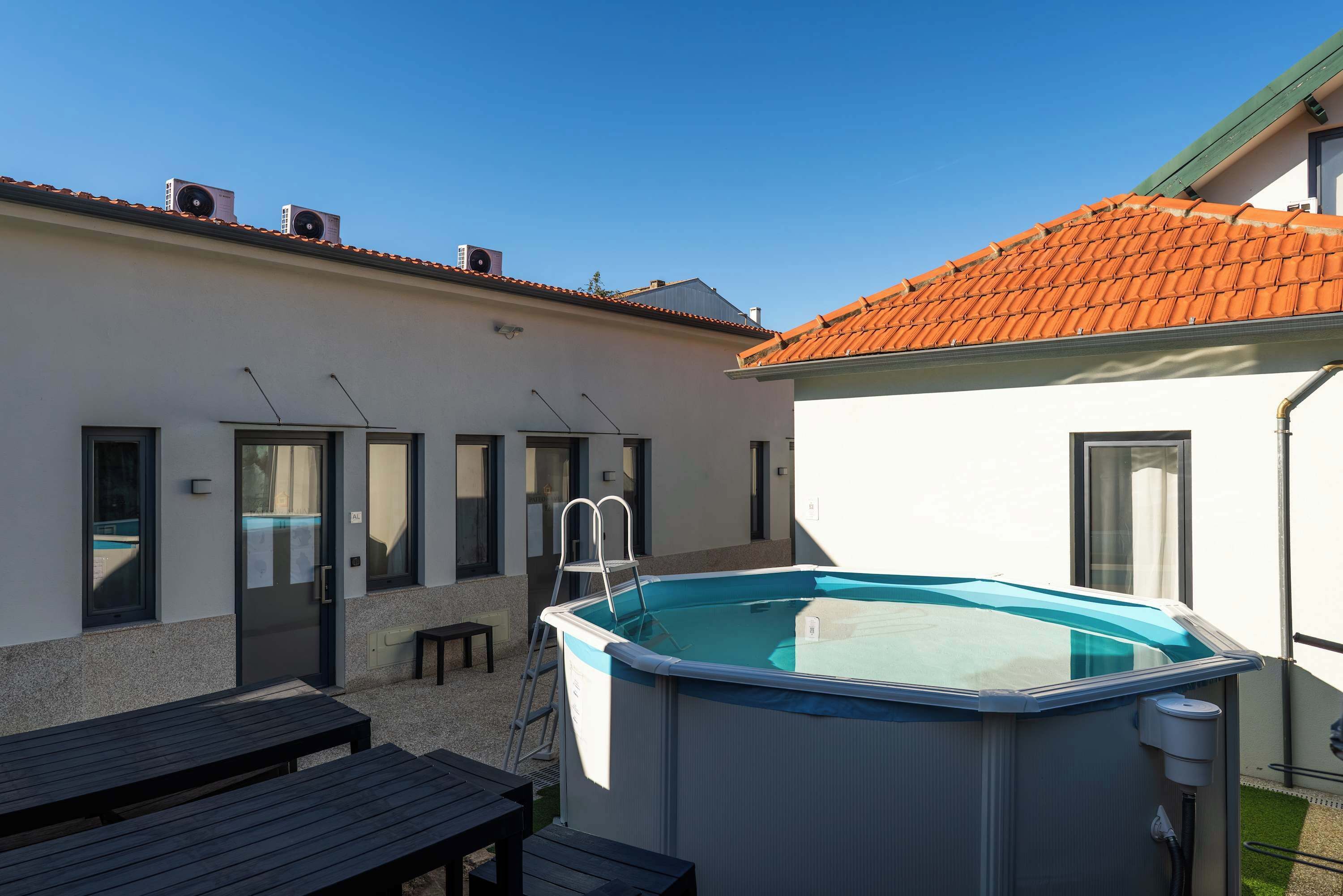 A swimming pool with a ladder, a wooden table, and a bench.